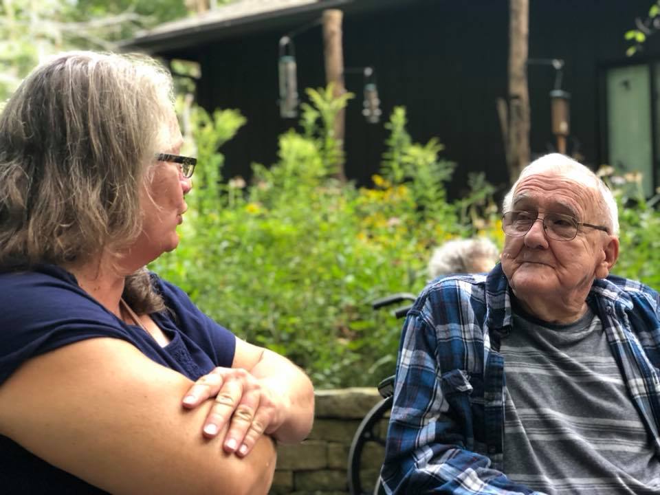 lady with folding arms chatting with older resident