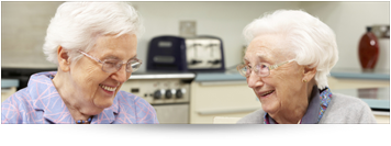 two older ladies sitting at kitchen area laughing