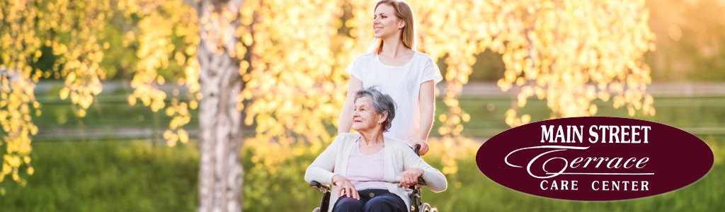 elder resident in wheelchair with staff standing behhind her